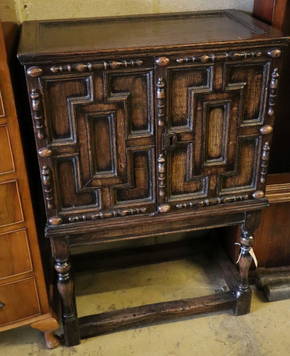 A 17th century and later oak cabinet of drawers enclosed by a pair of panelled doors, with retailers plaque, width 74cm depth 44cm hei